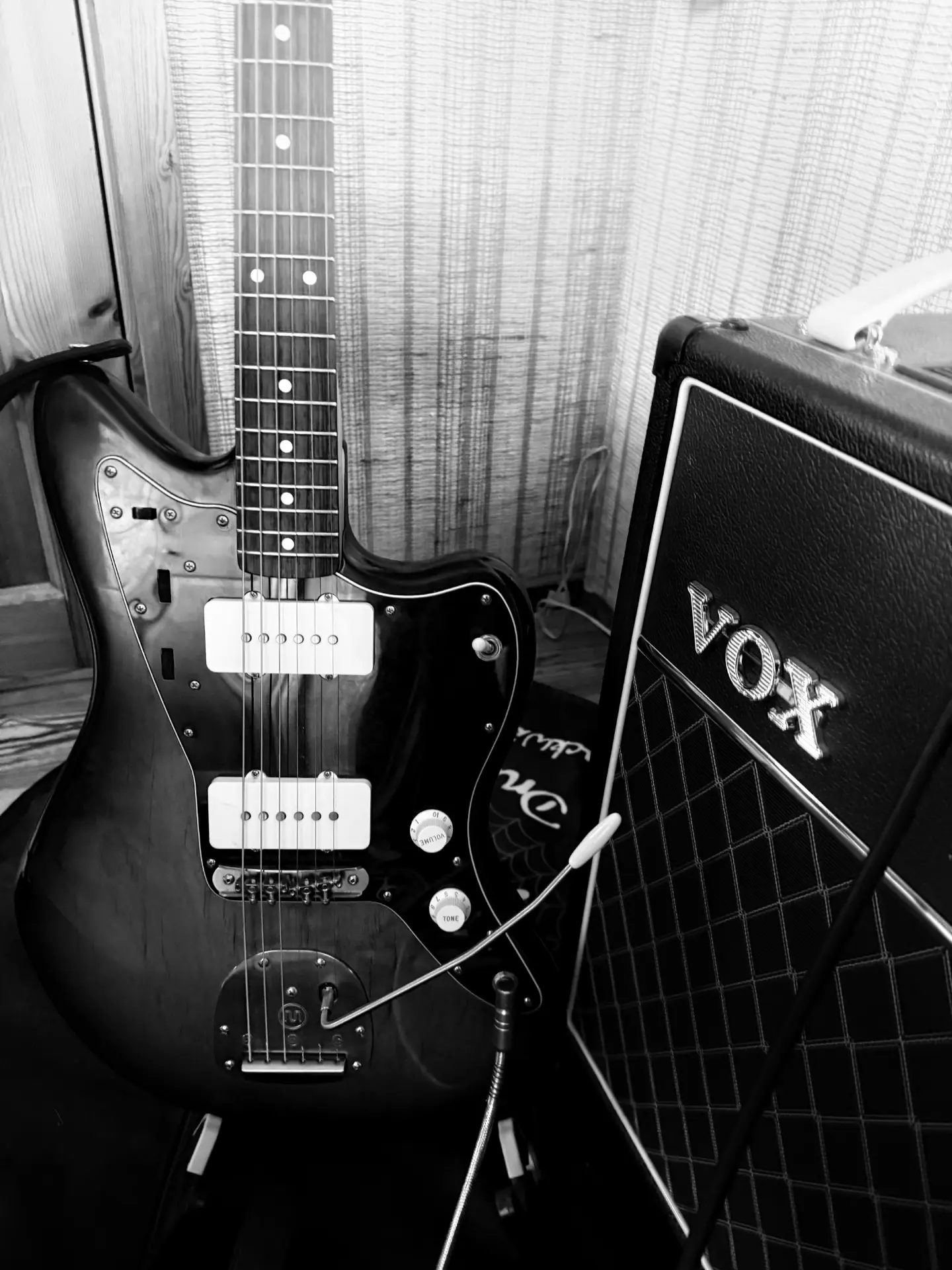Black-and-white guitar and Vox amplifier, moody backstage portrait